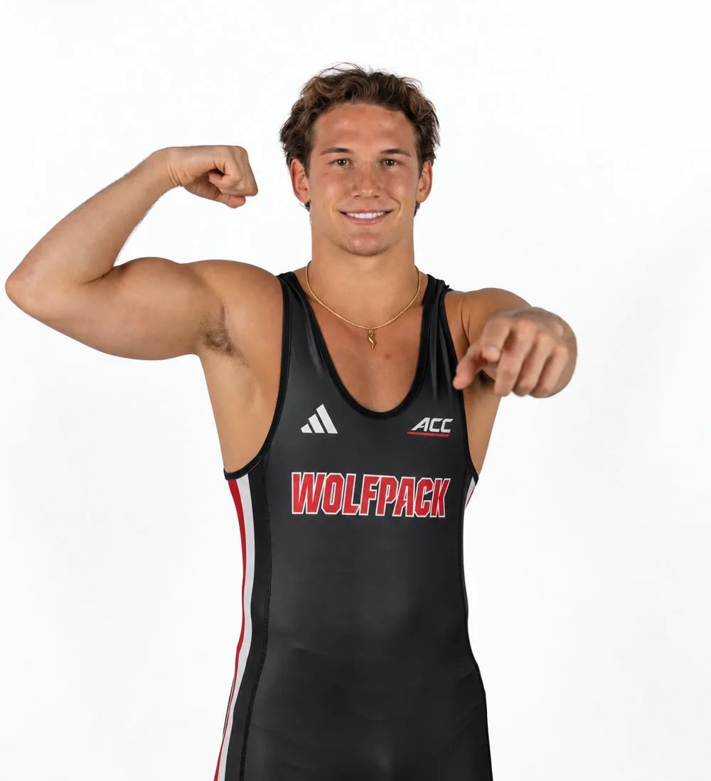 Jake Dailey in his NC State Wolfpack wrestling singlet, flexing and pointing at the camera